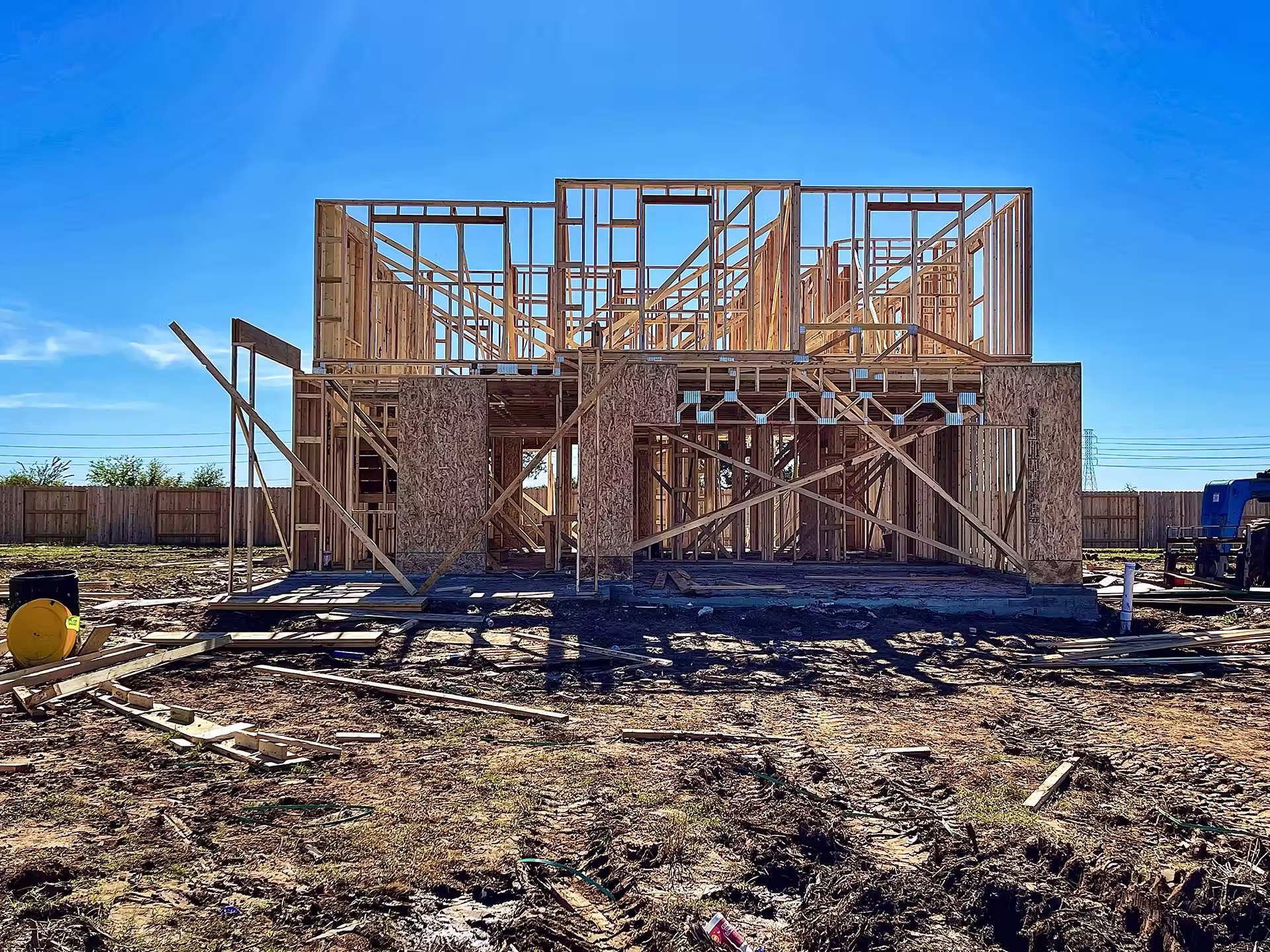 A two-story house under construction with exposed wooden framing
